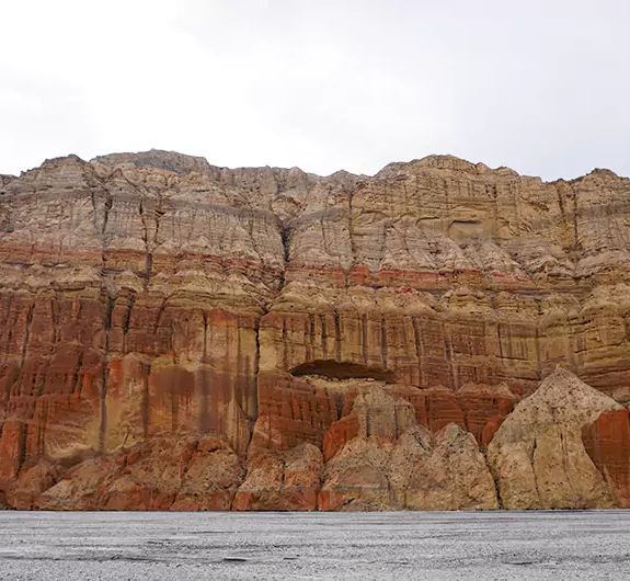 A huge red cliff beside the Kali Gandaki River as seen in a 14 days Upper Mustang trek