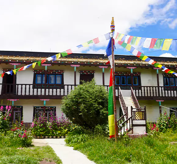 A beautiful Tea house with flowers in bloom and a prayer flag during the monsoon in the Upper Mustang Trek
