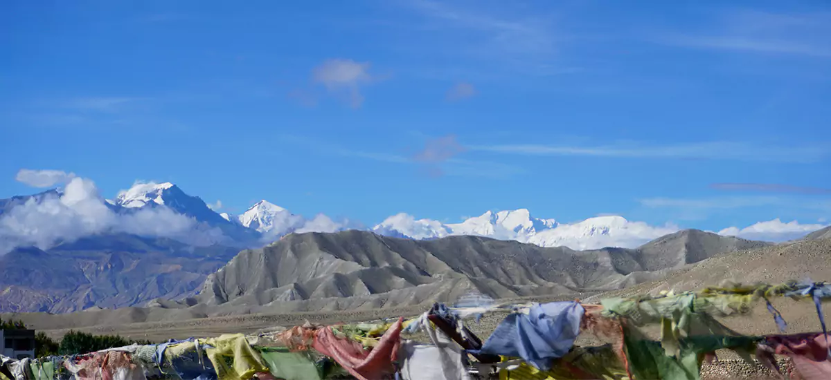 The contrast between a barren landscape & snow capped mountain in the Upper Mustang Trek